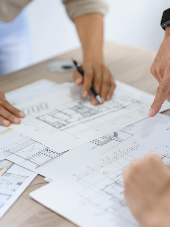 construction documents on table with fingers pointing