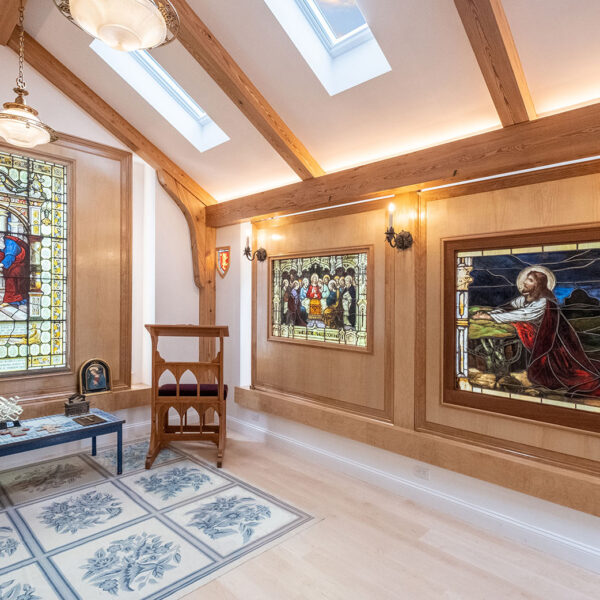 A wide-angle photograph depicts the religious art glass installed over large window panels in this custom home chapel designed by GF Architecture and built by M. Duffany Builders of Cape Cod.