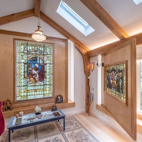 panels cover exterior windows while displaying artistic religious stained glass in a chapel added to a residence